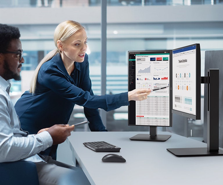 Kaks mees- ja naistöötajat arutavad kontoris monitori vaadates.