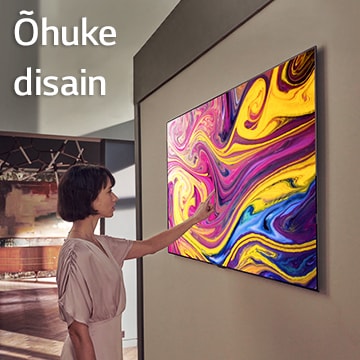 Naine vaatab seinal rippuvat telerit, mis näitab kunsti.