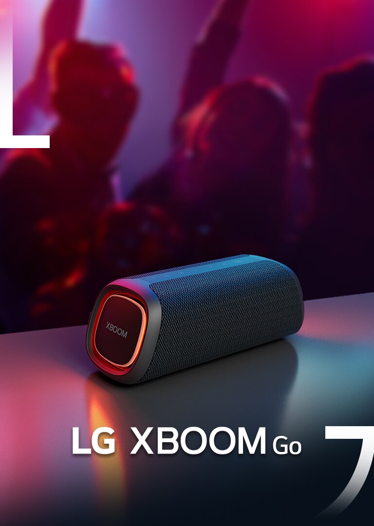 LG XBOOM Go XG5 on paigutatud metallist lauale, kus põleb oranž tuli. Laua taga naudivad inimesed muusikat.