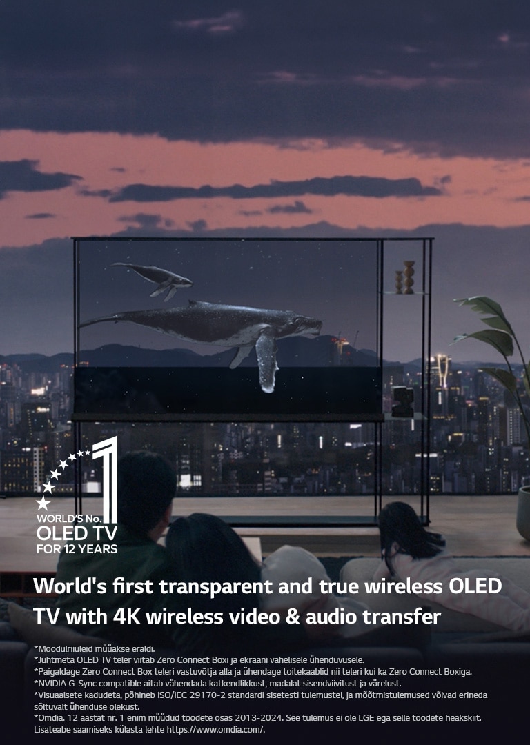 Vaal ujub üle LG SIGNATURE OLED TV teleri, kui laskub ruloo, paljastades õhtuse linnasilueti. Esiplaanil on inimesed, kes istuvad diivanil näoga teleri ja akna poole. Zero Connect Box asub väikesel laual telerist vasakul. 