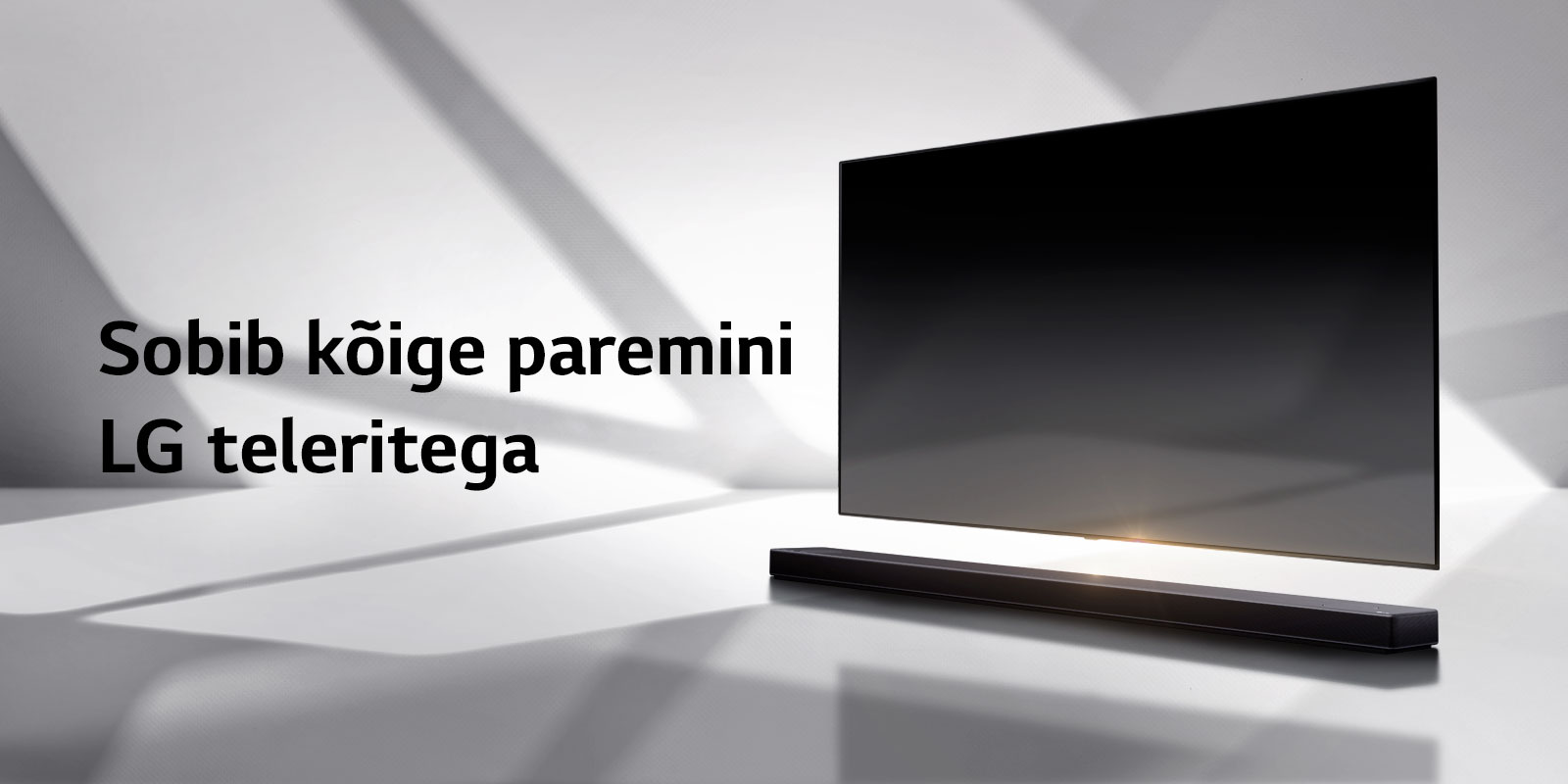 Soundbar ja teler on valgel põrandal ja väljaspoolt paremalt langeb tagant vari.