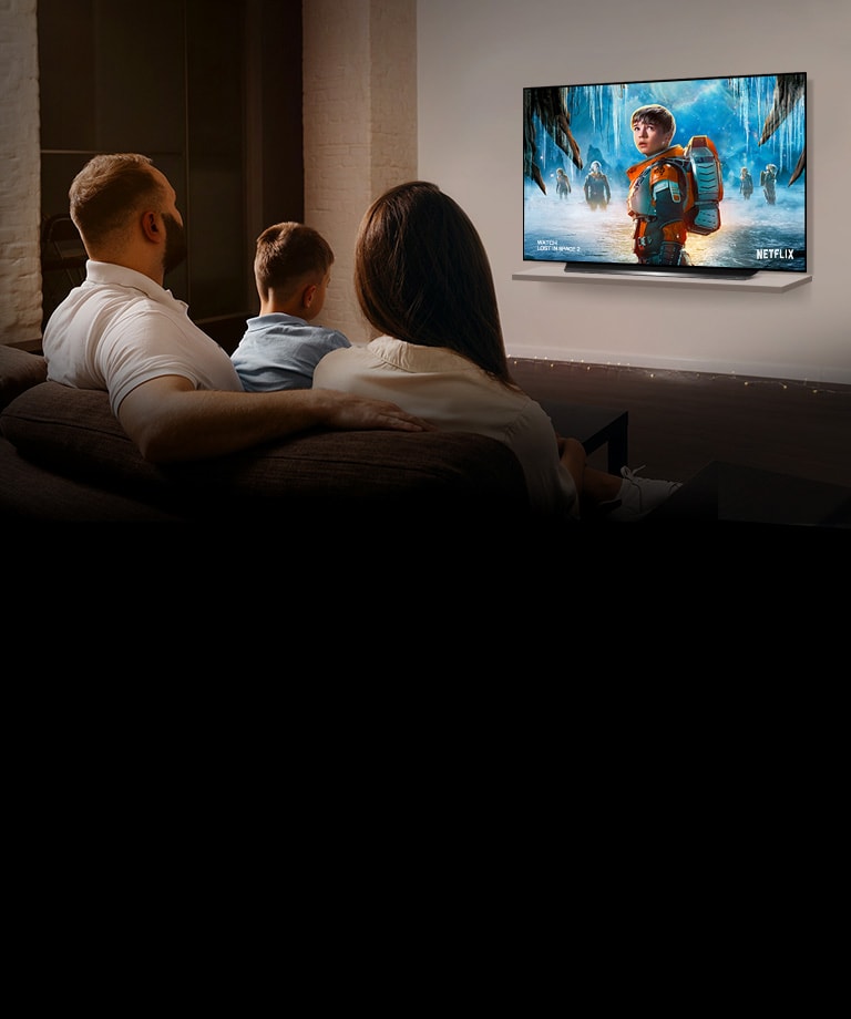 A couple sitting on a sofa in the living room watching LOST IN SPACE 2 series on TV