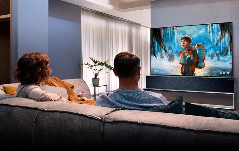 Elutoas diivanil istuv ja telerist armastusfilmi vaatav paar