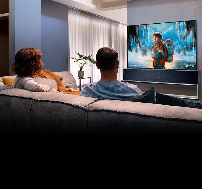 Elutoas diivanil istuv ja telerist armastusfilmi vaatav paar