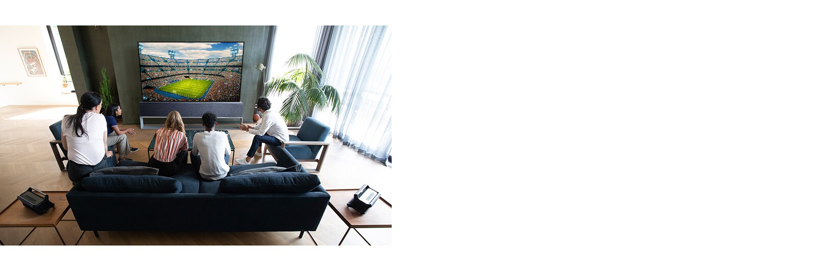 Elutoas telerist sportmängu vaatavad inimesed koos Bluetoothi tagakõlaritega