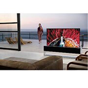 LG 65-tolline OLED 4K teler, Elutuba koos kokkurullitava teleriga, mis näitab vahtrate vahel asuvat koske, samal ajal kui terrassilt siseneb tuppa naine, OLED65RX9LA, thumbnail 11