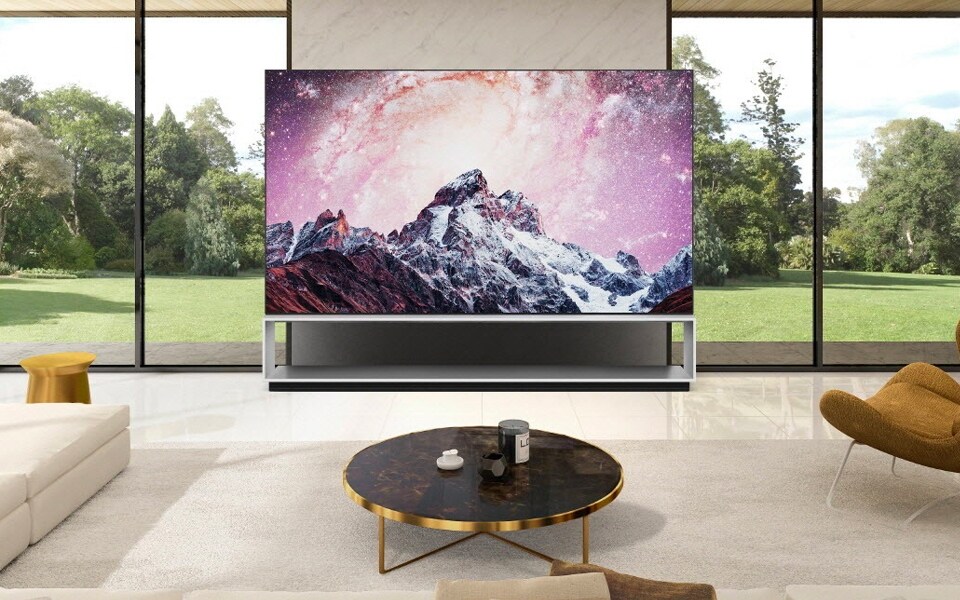 The LG SIGNATURE OLED TV R on a balcony showing a sunset that is similar to the sunset in the distance | More at LG MAGAZINE