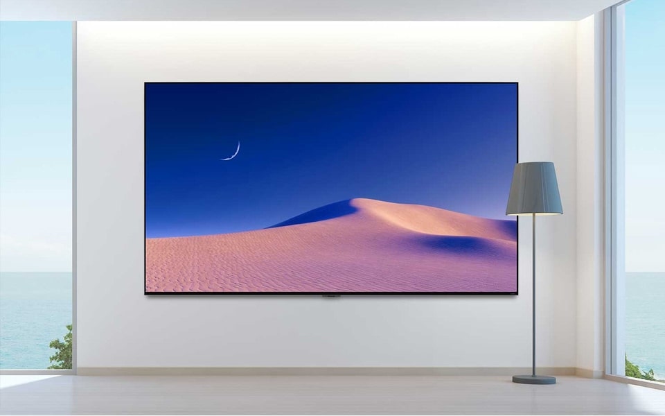 Desert sand dunes against a bright blue sky are displayed on a large LG TV screen.