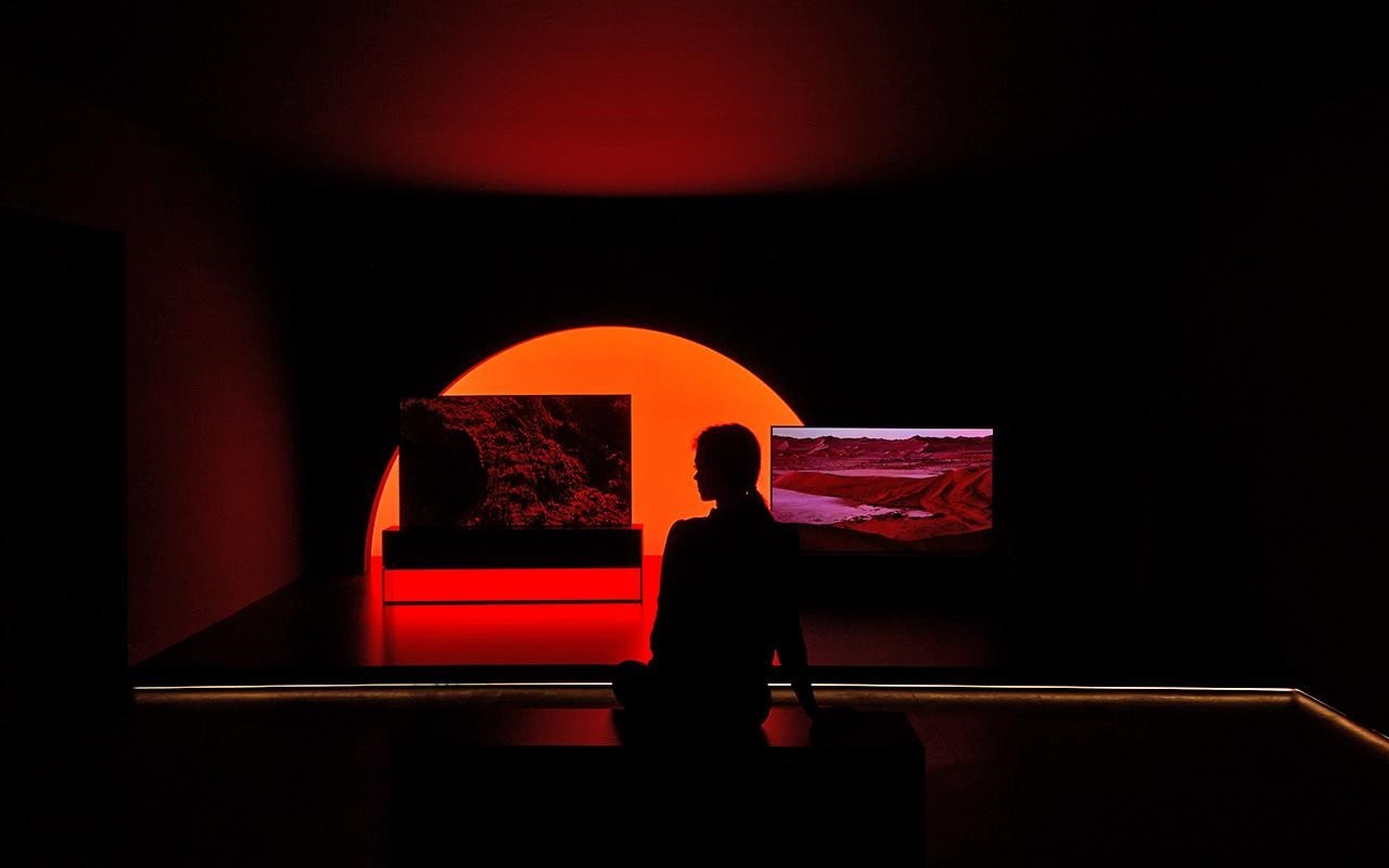 A woman sits in front of the LG SIGNATURE Rollable TV, on show at Milan Design Week | More at LG MAGAZINE