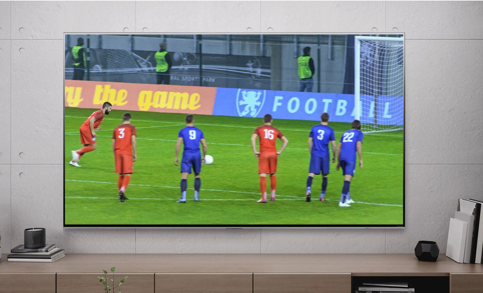 شاشة تلفزيون يظهر عليها أحد لاعبي كرة القدم خلال تسجيل ركلة جزاء (تشغيل الفيديو)