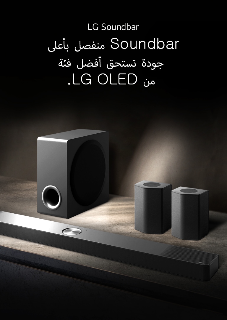 يتم وضع LG Soundbar، ومكبرات الصوت الخلفية، ومضخم الصوت ضمن منظور بزاوية على رف خشبي بني في غرفة سوداء، مُحاطة بالظلام ولا يُسلّط الضوء إلا على نظام الصوت.