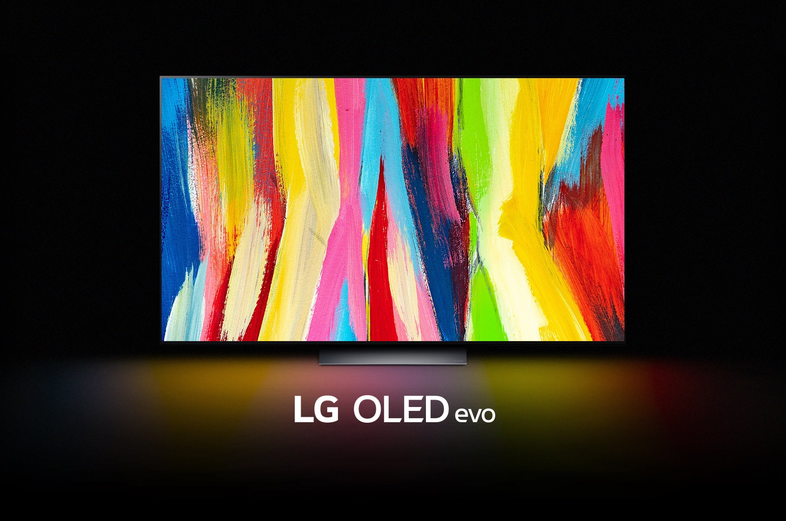 An LG OLED C2 is in a dark room with a colorful abstract artwork of vertical lines on its display and the words "LG OLED evo" underneath.