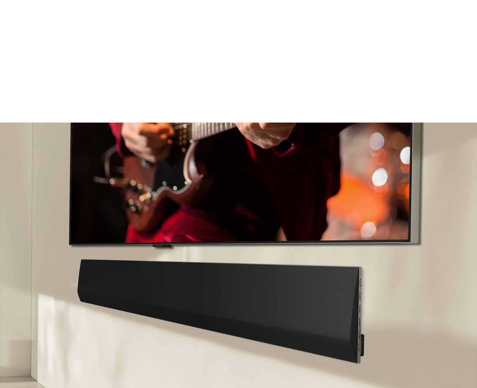 Una perspectiva en ángulo de la parte inferior de una barra de sonido LG y un televisor LG montada contra la pared.