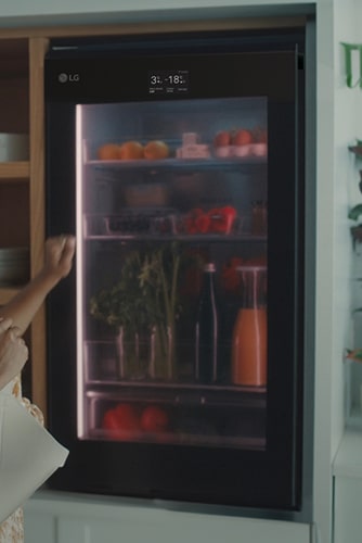 Image of a woman knocking on the top of a refrigerator.