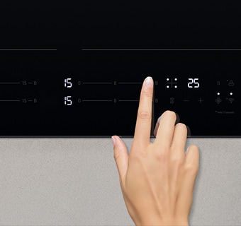 Imagen de mano tocando el panel de control de la placa de inducción.
