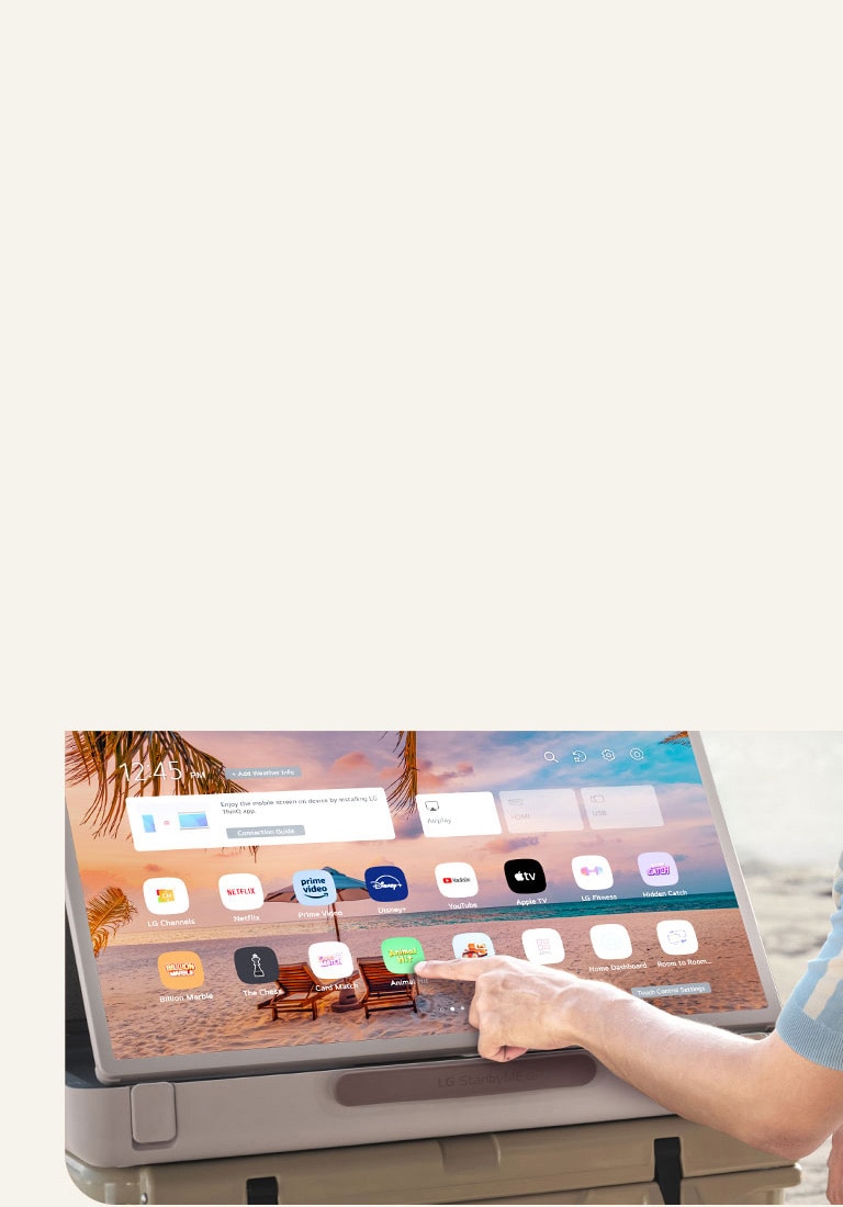 Primer plano del LG StanbyME Go. El producto está colocado sobre una mesa y la pantalla girada horizontalmente. Una mano toca un icono.