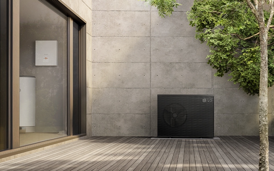 Casa moderna con terraza de madera, bomba de calor monobloque Therma V R290 y un árbol cerca
