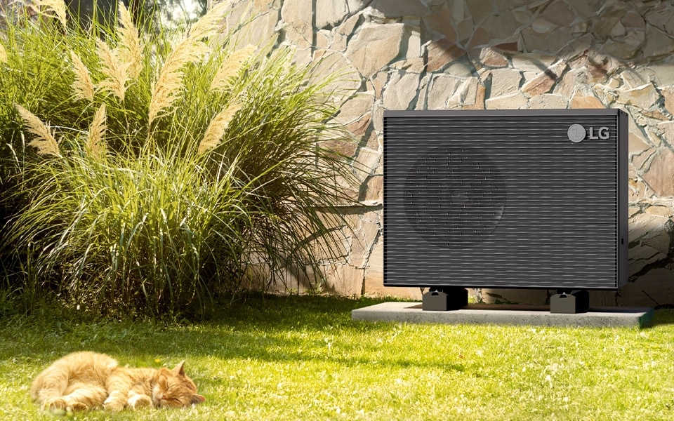 Bomba de calor monobloque Therma V R290 instalada en un jardín en la pared de una casa, demostrando su elegante diseño y funcionalidad.