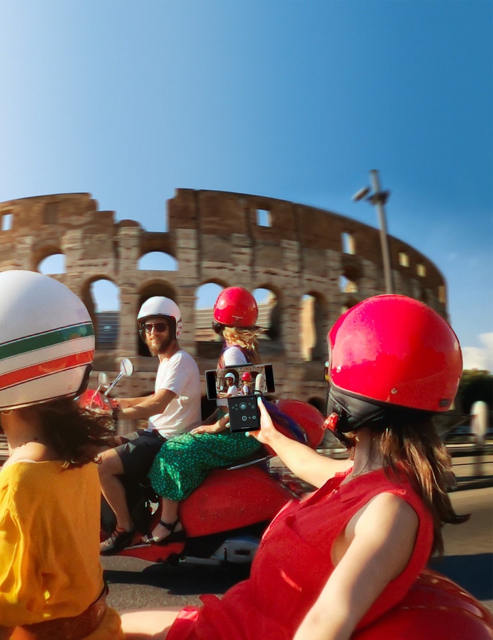 A woman recording herself on the LG WING while riding vespa past the Colosseum in Rome