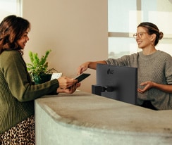 Ystävällinen vastaanottovirkailija näyttää naiselle, mihin allekirjoittaa digitaalisella tabletilla.