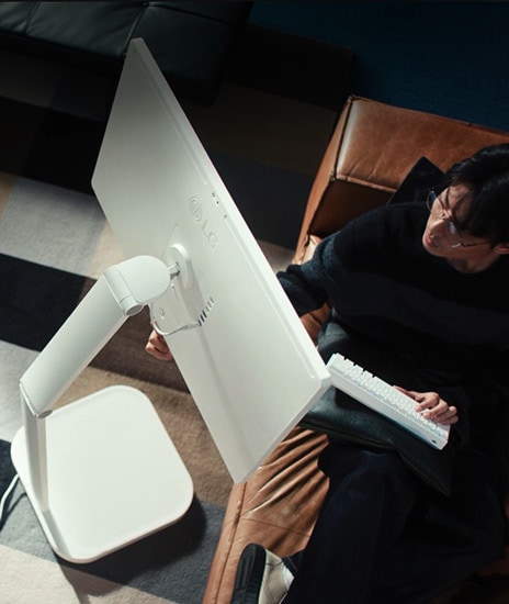 Mies pitää näppäimistöä yhdellä kädellä ja koskee samalla LG Smart Monitor Swingiä toisella kädellään.