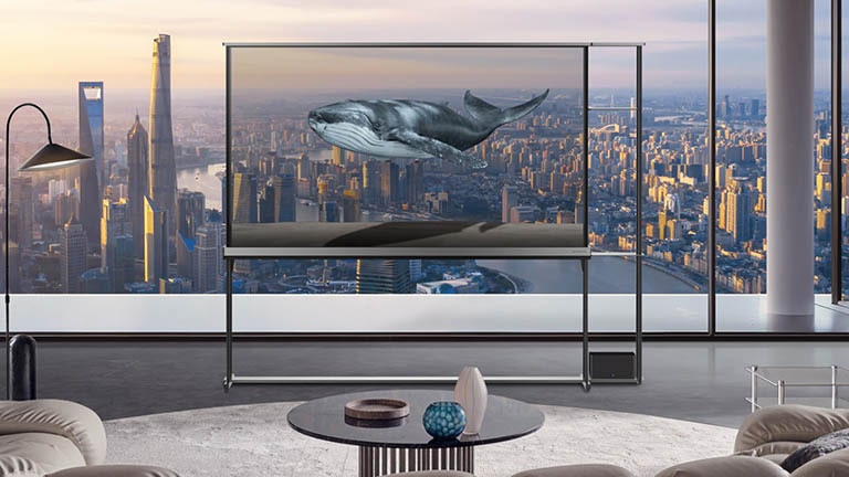 Erilaiset näkymät näyttävät epätodellisen kuvan LG Signature OLED T:n ollessa läpinäkyvyystilassa. Kaupunkimaisema ja ilotulituksia, lintu ottamassa jotain pienestä puusta ja kaloja jättimäisessä akvaariossa. LG Signature OLED T:n näytön ansiosta näkymät näyttävät sekoittuvan todelliseen taustaan.