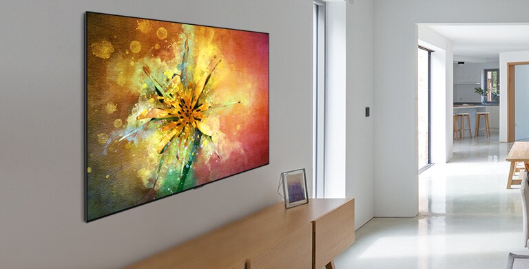 Olohuoneessa on sohva ja televisio, jossa näkyy ilmakuva luonnosta