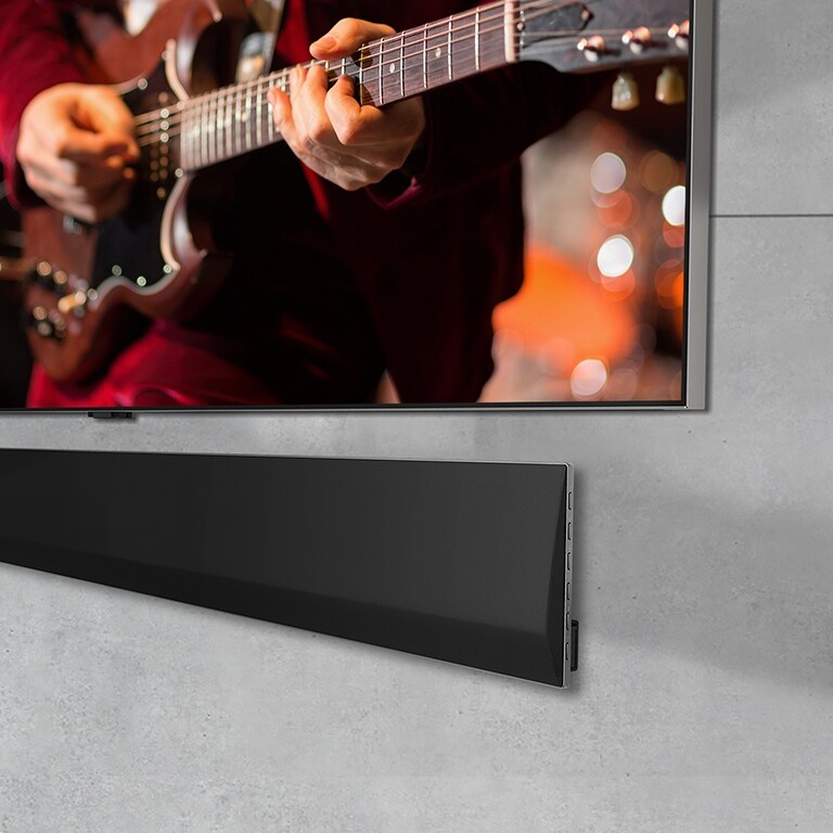 Kulmasta otettu lähikuva LG OLED TV -laitteen pohjasta ja seinälle asennetusta LG Soundbar -äänipalkista.