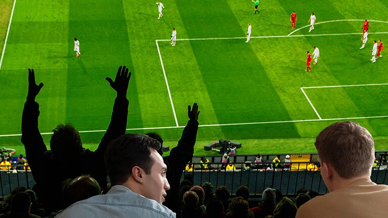 Ihmiset katsovat urheilua olohuoneessa ultrasuuresta televisiosta