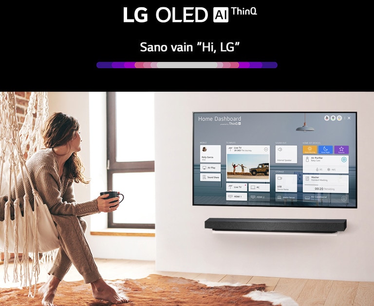 Nainen istuu olohuoneen tuolilla ja televisiossa näkyy Home Dashboard.