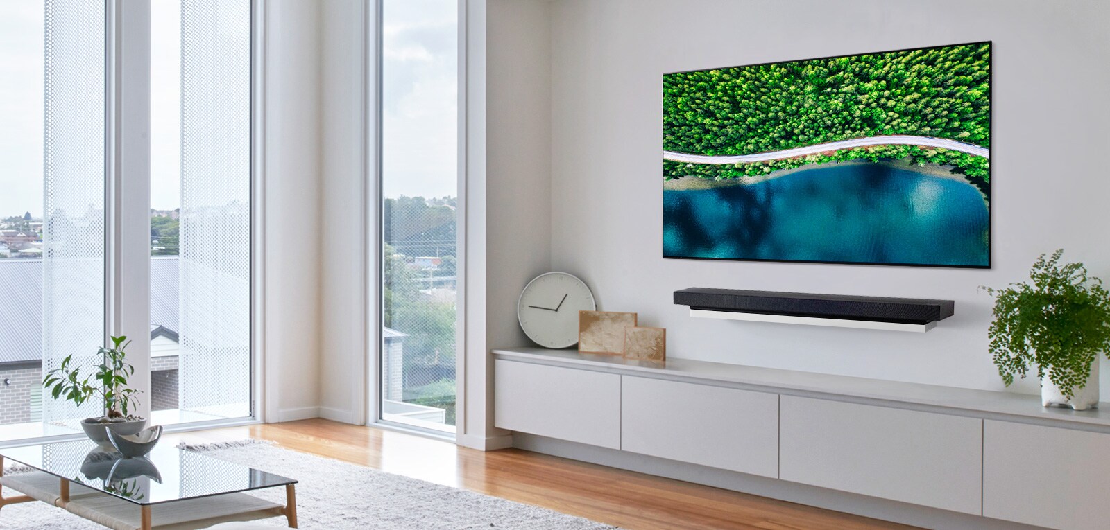 Olohuoneessa on harmaa tuoli ja televisio, jossa näkyy ilmakuva luonnosta