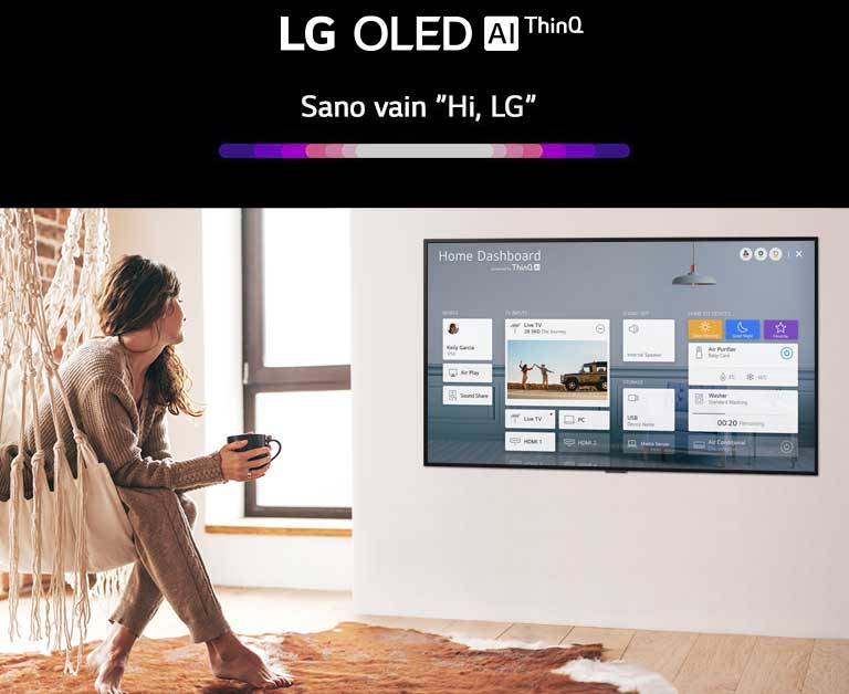 Nainen istuu olohuoneen tuolilla ja televisiossa näkyy Home Dashboard.