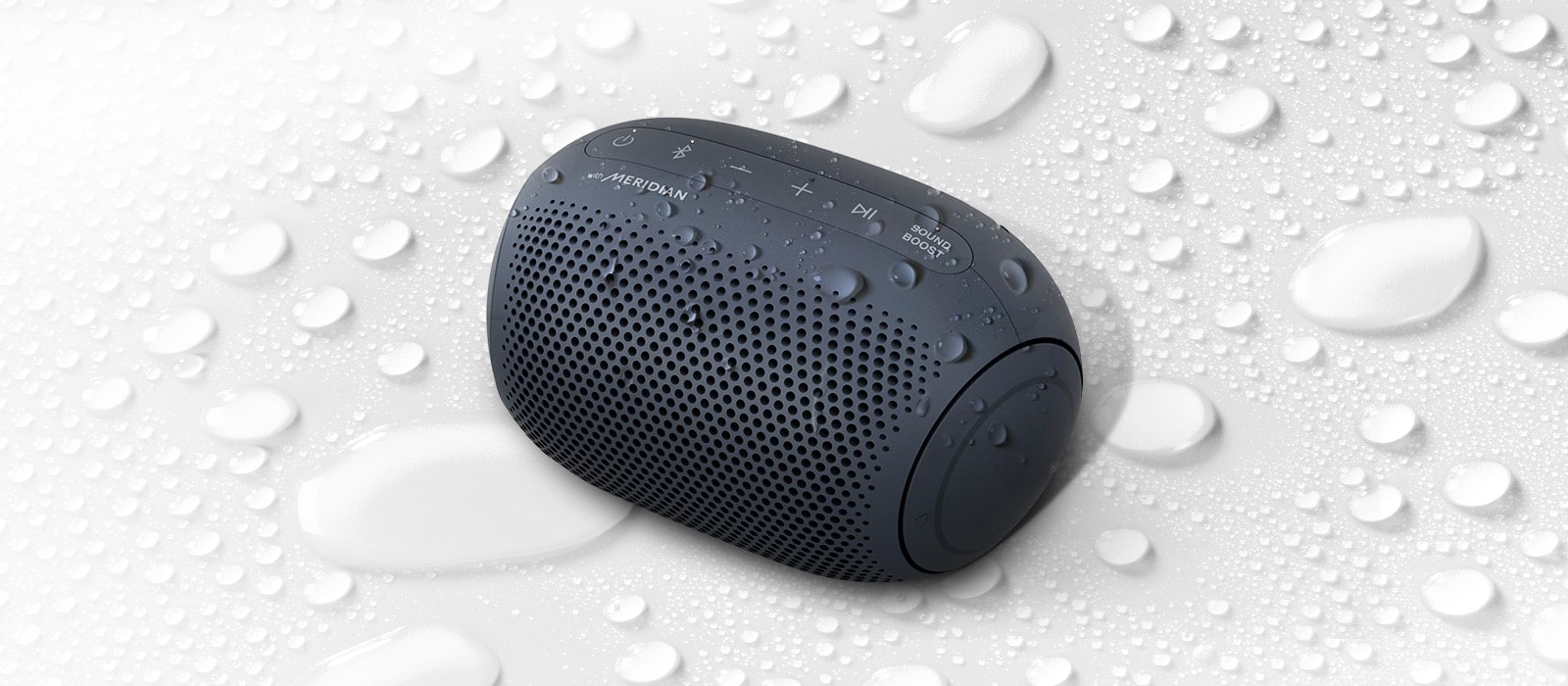 Valkoisella taustalla LG XBOOM Go osoittaa ylöspäin vasemmalle. LG XBOOM Gon pinnalla ja alapuolella on vesipisaroita.