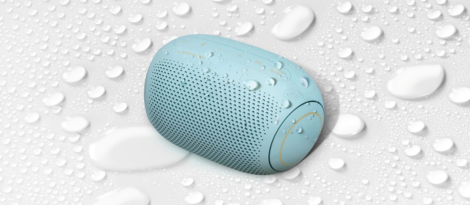 A top view of an LG XBOOM Go PL2B on a white surface with water droplets