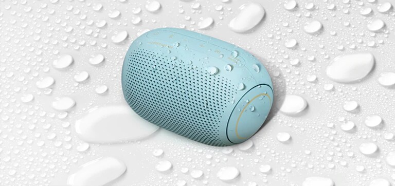 A top view of an LG XBOOM Go PL2B on a white surface with water droplets