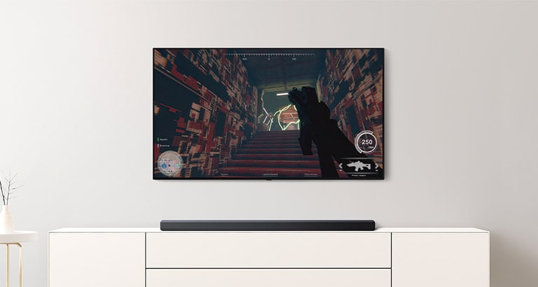 Olohuoneessa on TV ja soundbar-kaiutin. FPS-peli TV-ruudulla ja TV-kanava vaihdetaan jalkapallopeliin (toista video).