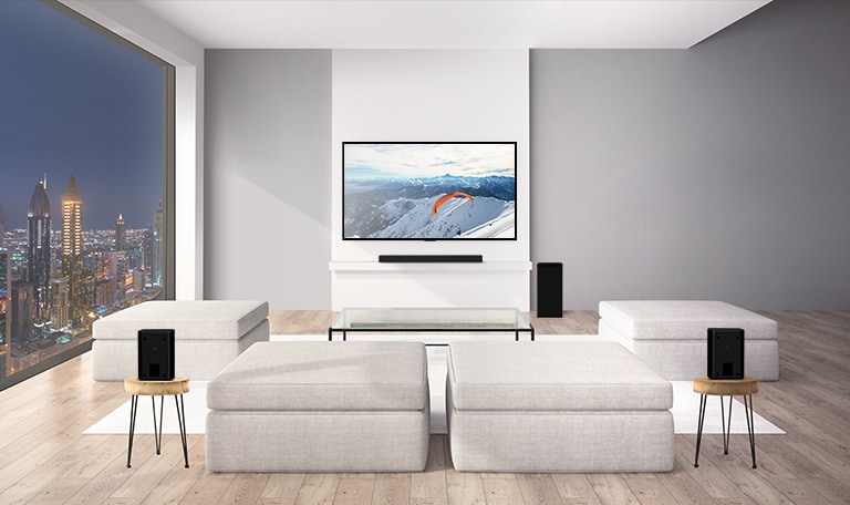 Olohuoneessa on LG Soundbar, alibassokaiutin ja kaksi takakaiutinta. Grafiikka ääniaalloista, jotka kulkeutuvat takakaiuttimista kattoon ja kimpoavat takaisin (toista video).