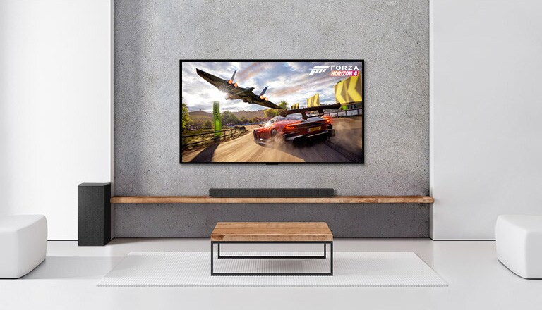 Kaksi takakaiutinta, alabassokaiutin, soundbar-kaiutin ja TV ovat valkoisessa olohuoneessa TV-ruudulla ajava auto ja avaruusalus