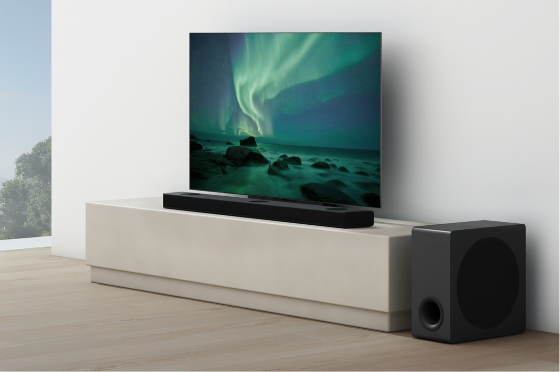 LG Soundbar S95QR, Soundbar-kaiutin on television alla valkoisessa olohuoneessa ja alabassokaiutin on sen oikealla puolella., S95QR, thumbnail 5