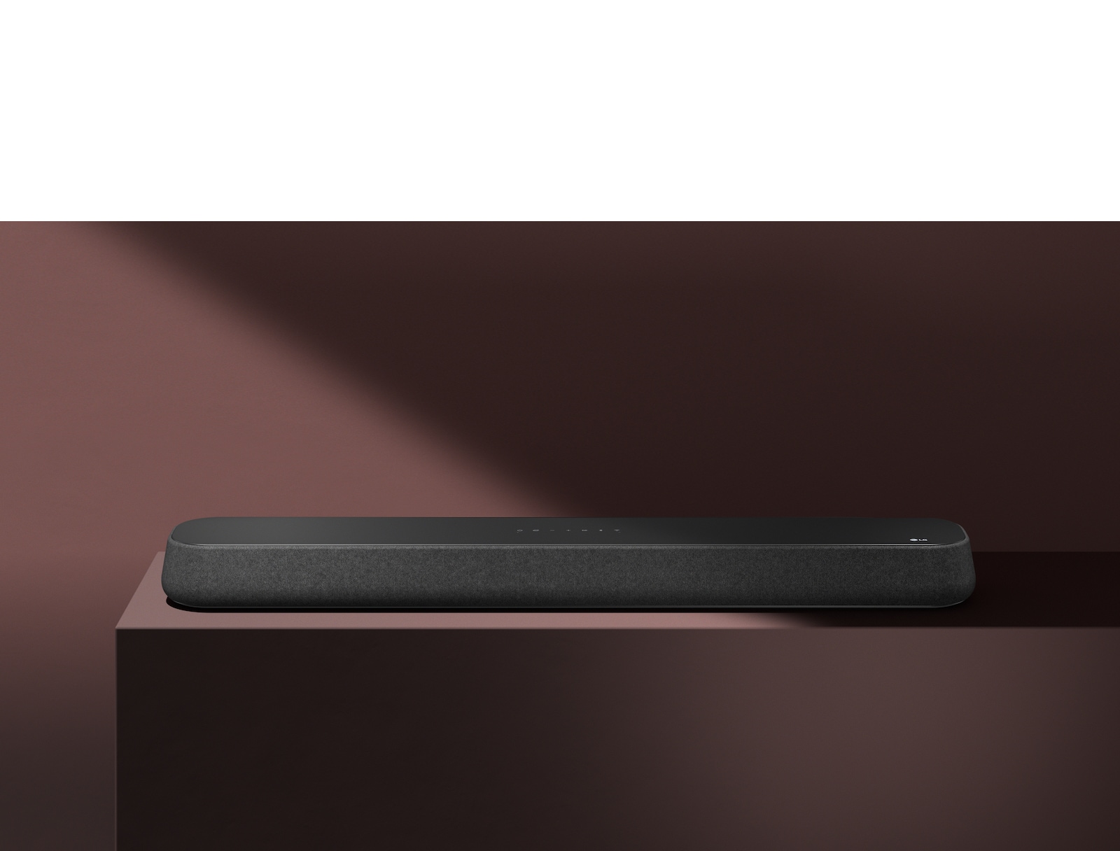 LG Sound Bar SE6S on punaisen laatikon päällä punaisen taustan edessä. Musta varjo peittää kuvan oikean yläpuolen.