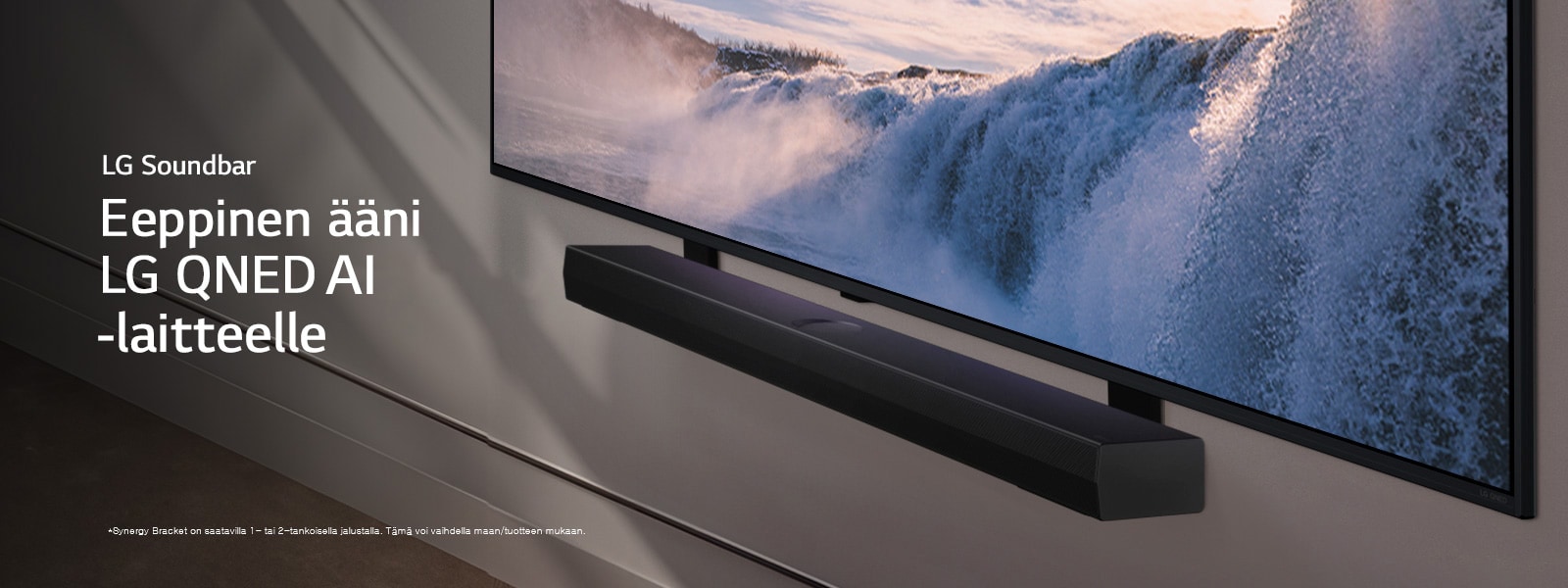 LG TV ja Soundbar näkyvät seinällä kulmasta. Televisiossa on lähikuva suuresta vesiputouksesta, ja aurinko valaisee seinää, televisiota ja äänipalkkia. Vastuuvapauslausekkeessa lukee: ”Synergy Bracket on saatavilla 1- tai 2-tankoisella jalustalla. Tämä voi vaihdella maan/tuotteen mukaan.”