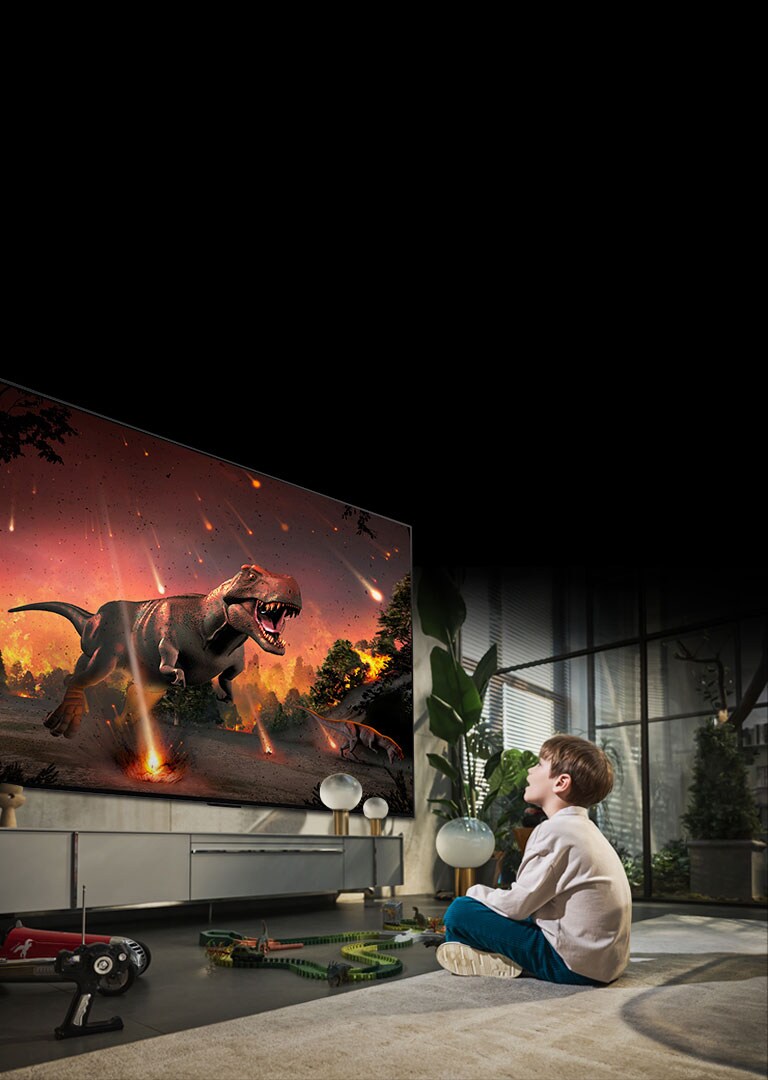 Kuva nuoresta pojasta, joka istuu lattialla 97-tuumaisen LG OLED G2:n edessä. Hän katsoo hämmästyneenä hyperrealistista dinosauruselokuvaa valkokankaalta.