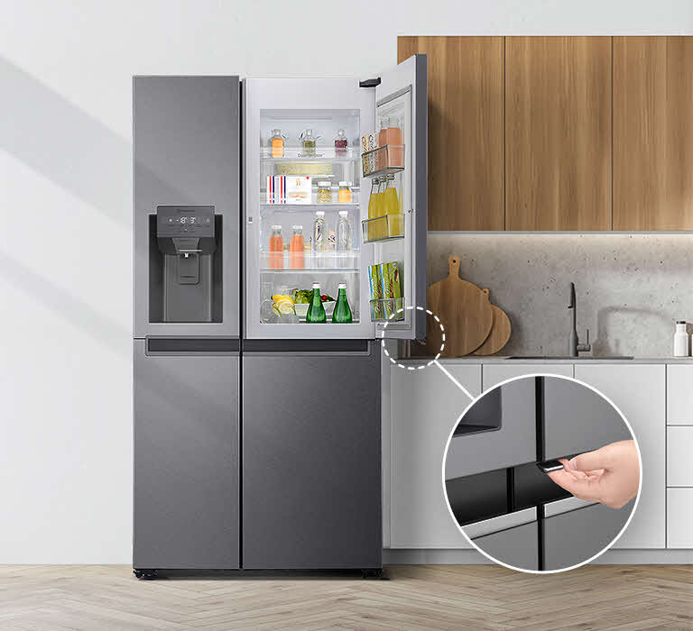 A front view of the refrigerator installed in a kitchen. The top right door is open and there is a circle and a line leading to a larger circle that shows a magnified view of the button on the bottom left corner of the open door which has a concealed opening button.