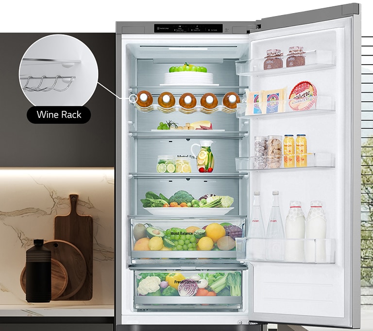 Avoinna oleva jääkaappi, jonka hyllyt on täytetty tuoreilla elintarvikkeilla. Jääkaapissa näkyy viinipulloteline ja taittuva hylly.