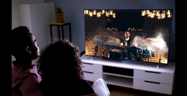 Couple sitting on a couch watching movie on TV (move the slide)