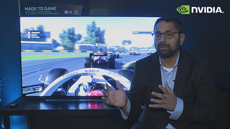 Kaustubh Sanghani giving an explanation in front of a screen showing a racing game (play the video)