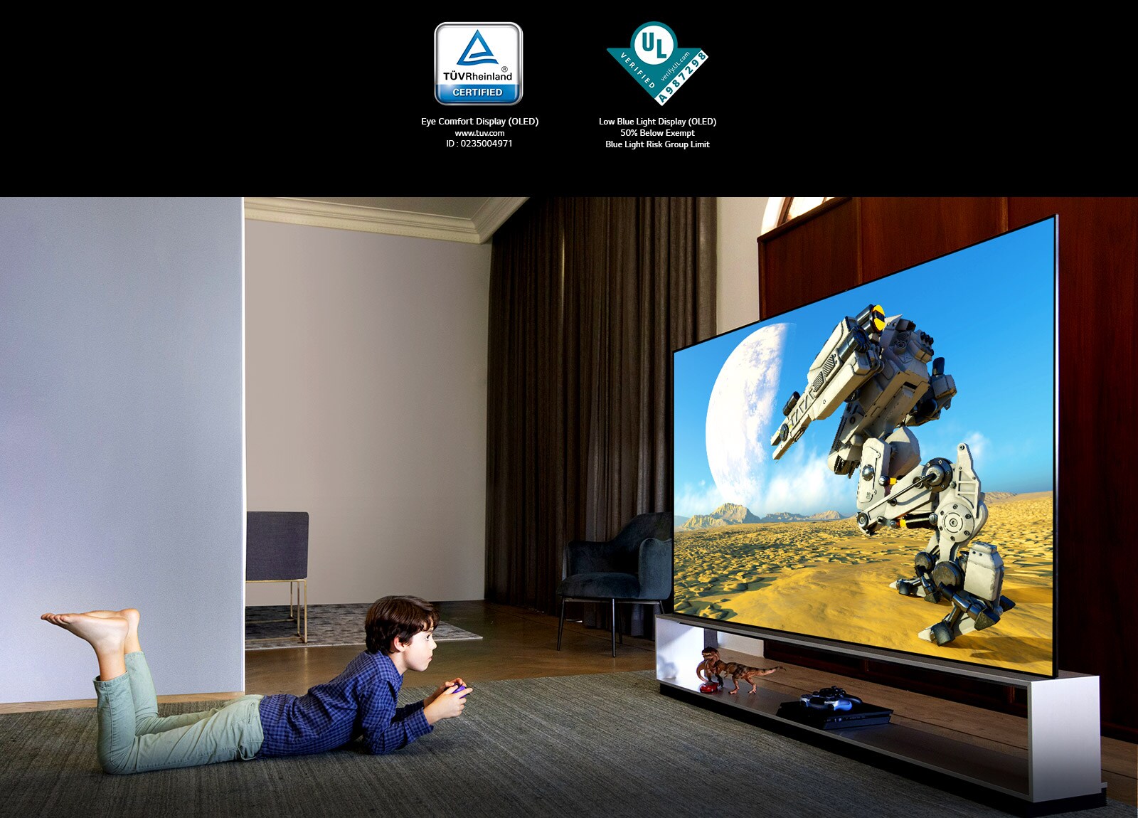 Boy lying on his stomach in front of a large TV with controllers in his hands,