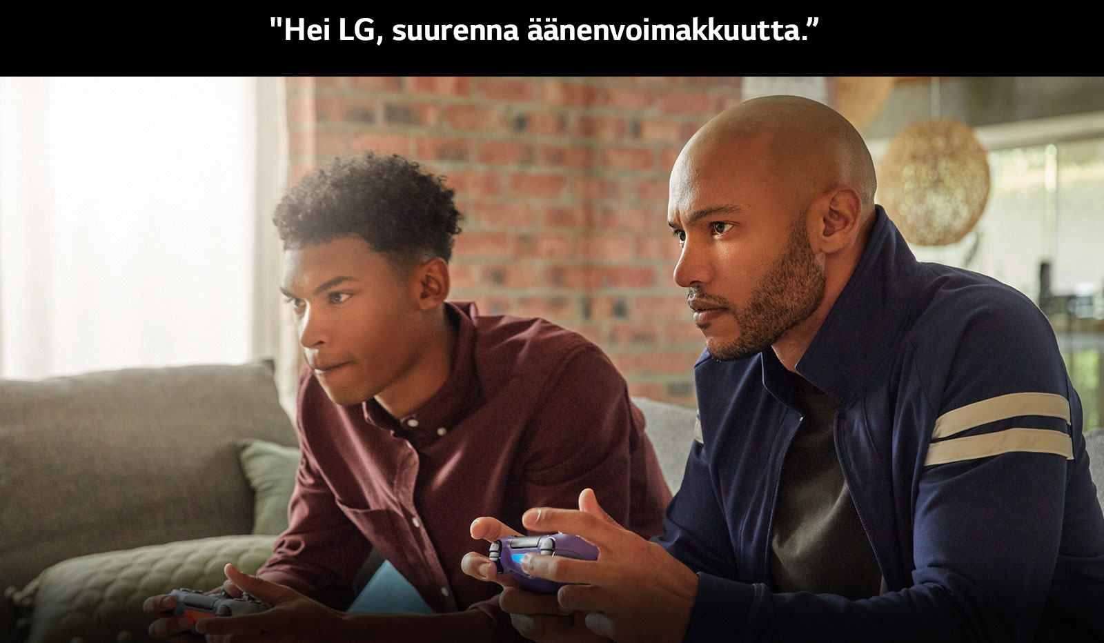 Two guys on the couch holding wireless game controllers, immersed in a game