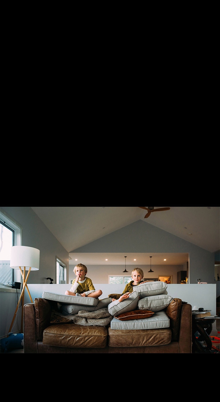 Kaksi kaksospoikaa istuu sohvalla katsellen jotain.