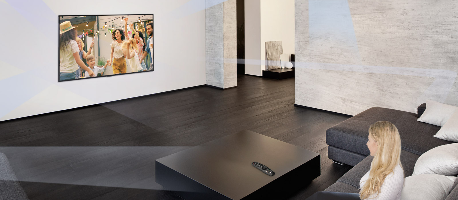 Nainen suuressa ja minimalistisessa olohuoneessa katsoo TV:tä, jossa näkyy tanssivia ihmisiä